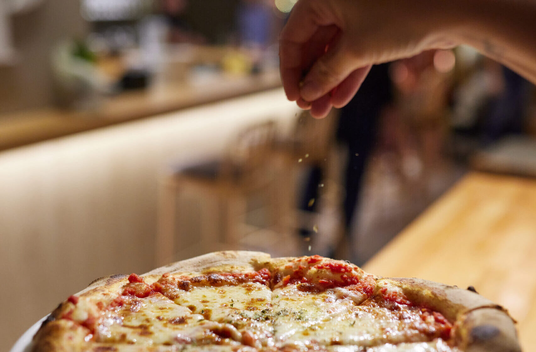 Añadiendo ingredientes sobre una pizza recién horneada